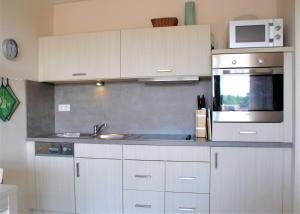 a kitchen with white cabinets and a sink and a microwave at Apartment 29 "Heimathafen 29", Apartmenthaus Hafenspitze, Blickrichtung InnenstadtBinnenhafen in Eckernförde