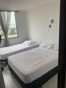 Apartamento vacacional, Ricaurte في ريكورت: سريرين توأم في غرفة بها نافذة +8 صور