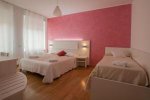 ローマにあるB&B Momenti Romaniのピンクの壁のベッドルーム1室(ベッド2台付)