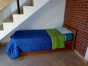 a bed with a blue and green blanket next to a brick wall at Cabaña Pope 2 in Federación