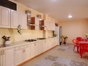 cocina con armarios blancos y comedor con mesa en Raduga Guest House, en Lazarevskoye