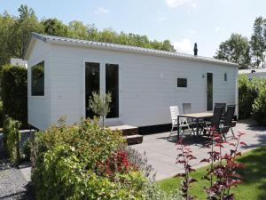 a white shed with a table and chairs in a garden at Chalet in Friesland near Wadden Sea in Tzummarum