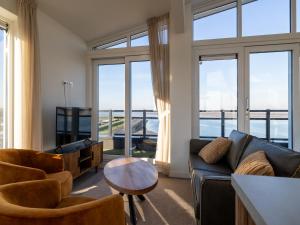 a living room with a couch and chairs and windows at Penthouse in Sint-Annaland by the Beach in Sint Annaland