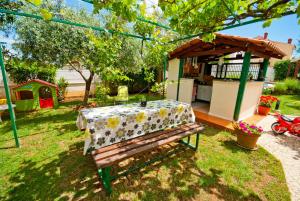 un banc en bois avec une table dans l'arrière-cour dans l'établissement Guest house Bizjak, à Vinkuran