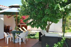 a patio with a table and chairs and a tree at Apartamentos Costa in Costa da Caparica