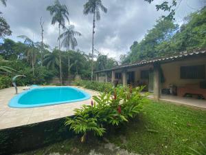 a swimming pool in a yard next to a house at Chácara Gomes - Caiubura - Bertioga in Bertioga