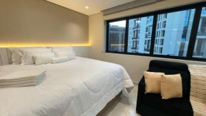 a bedroom with a large white bed and a chair at M N Flats Apartamento Dentro Do Hotel Av Ibirapuera 2534 in Sao Paulo