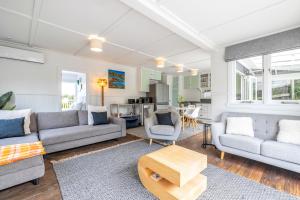 a living room with two couches and a table at Little Oneroa Gatehouse in Waiheke Island