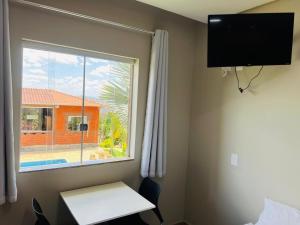a room with a desk and a window with a view of a house at Pousada Hilário ltda in São João del Rei