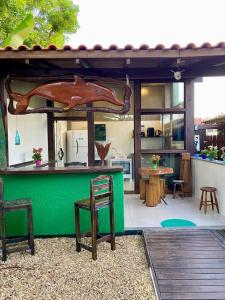 un ristorante con bancone verde con sedie e tavoli di Hospedaria aconchego 4 a Garopaba