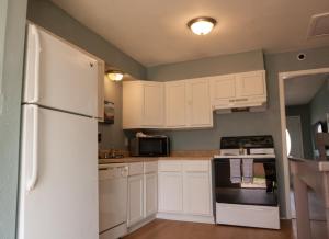 a kitchen with white cabinets and a refrigerator at Near Kyle Field - Cottage Close To Campus in College Station +13 photos