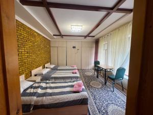 a room with four beds and a table and chairs at Panjrud guest house in Panjakent