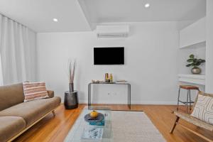 ハミルトンにあるElegant Hamilton East Home Near Gardens and Cafesのソファと壁掛けテレビのあるリビングルーム