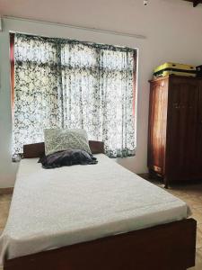łóżko w pokoju z dużym oknem w obiekcie Two-room cottage kandy w mieście Kandy