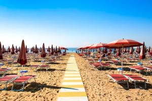 a sandy beach with chairs and umbrellas and the ocean at Jesolo Sun Beach House - Host Solution in Lido di Jesolo