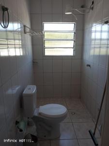 a white bathroom with a toilet and a window at Pousada Mar e Sol Indaiá in Bertioga