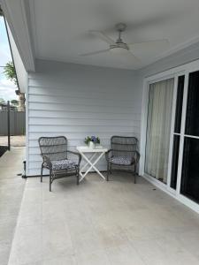 a patio with two chairs and a table on a house at Magnolia Little Gem in Alstonville