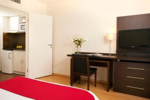 um quarto com uma secretária, uma televisão e um tapete vermelho em Residhome Toulouse Tolosa em Toulouse