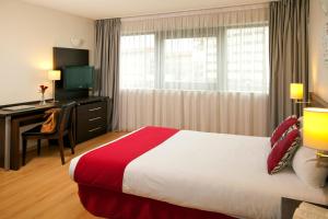 Habitación de hotel con cama, escritorio y TV. en Residhome Toulouse Tolosa, en Toulouse