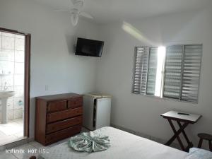 a bedroom with a refrigerator and a sink and a window at Pousada Mar e Sol Indaiá in Bertioga