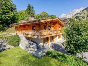 a large wooden house with stairs in the grass at Chalet luxe 5★, 6 pers, hammam, près des pistes, 3 chambres - FR-1-304-305 in La Clusaz