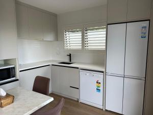 a kitchen with white cabinets and a table and a refrigerator at Beautiful Lakeview Apartment in Taupo