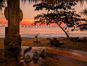 a statue sitting on a bench next to the beach at KAMAKU Bungalows - Sunset Beach in Koh Rong Sanloem