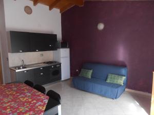 a living room with a blue couch and a kitchen at La Rosa dell'Etna in Castiglione di Sicilia