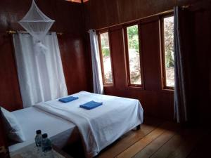 a bedroom with a bed with two blue towels on it at Watuburu Cottage & Restaurant in Kelimutu