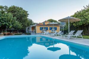 a swimming pool with chairs and an umbrella and a house at Billy's House in Vasiliki
