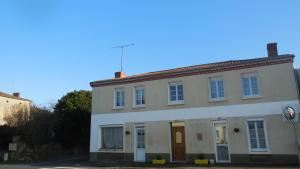 a white building with a brown door on a street at L'Ancien p'tit bistrot in Saint-Hilaire-du-Bois