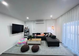 a living room with a couch and a tv at Premium Snooze Queen Bed Petite Room in Caroline Springs