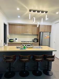 a kitchen with a island with bar stools at Premium Snooze Queen Bed Petite Room in Caroline Springs