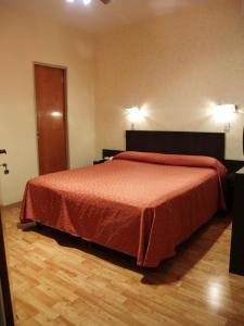 a bedroom with a bed with a orange bedspread at Hotel El Cabildo in Buenos Aires