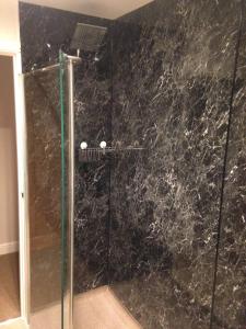 a bathroom with a shower with a black marble wall at The Wheatsheaf in Crick