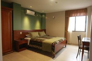 a bedroom with a bed with a green wall at Hotel Puerto Banana in El Guabo