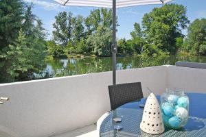 una mesa con sombrilla en el balcón con vistas al río en Maisonette-Wohnung mit großer Terrasse - 11a, en Maximiliansau
