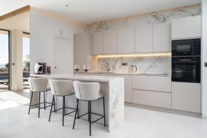 a kitchen with white cabinets and bar stools at Luxury Villa Hedonia in Brela