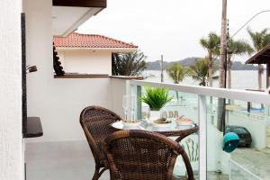 a table and chairs on a balcony with a view of the water at Pousada Gaúcha in Bombinhas