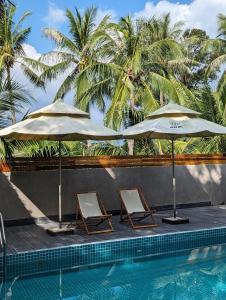 2 sillas y sombrillas junto a una piscina en Wam Hou, en Phu Quoc