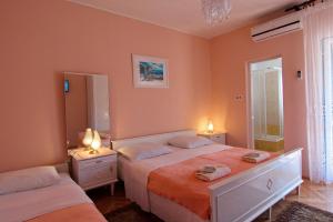 dwa łóżka w sypialni z pomarańczowymi ścianami i dwoma lampami w obiekcie Apartment and Rooms Toka w mieście Zadar