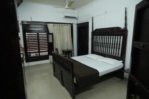 ein Schlafzimmer mit einem Bett mit weißer Bettwäsche und einem Fenster in der Unterkunft Heritage Villa in Mangaluru
