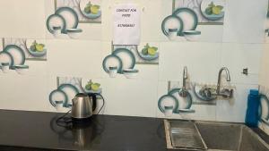 a kitchen with a sink and a wall with cups at Aadya's Blessed Home in Prayagraj