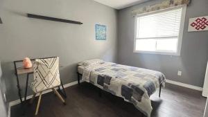 Un dormitorio con una cama y un escritorio y una ventana. en Monthly Accommodation Edmonton Londondery, Pilot Sound, McConachie Area, en Edmonton