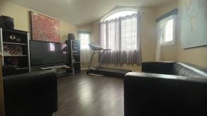 Una sala de estar con un sofá y un televisor. en Monthly Accommodation Edmonton Londondery, Pilot Sound, McConachie Area, en Edmonton