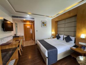 una camera d'albergo con un letto grande e una scrivania di GMS Grand Boutique Hotel ( A Unit of GMC Hotel & Resorts) a Dehradun