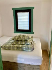 a bed with a pillow and a window in a room at Leśne Domki Premium in Prokowo +4 photos