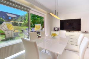 a dining room with a white table and chairs and a large window at Windeby 1T in Wenningstedt