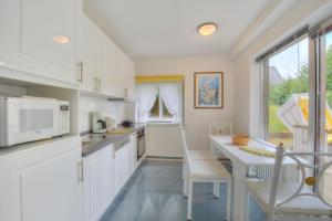 a kitchen with white cabinets and a table with a microwave at Windeby 1T in Wenningstedt
