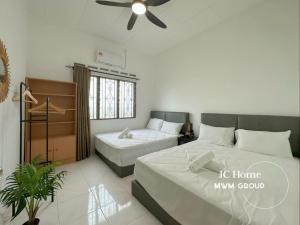 a bedroom with two beds and a ceiling fan at Kempas Kampung style 12pax Family Suites in Johor Bahru